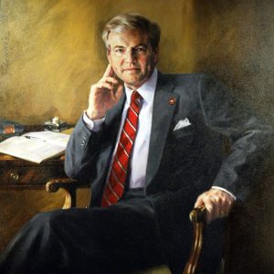 White man posing at his desk with his right hand raised to his ear