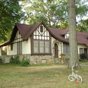 Two-story Tudor house with stone foundation and trees