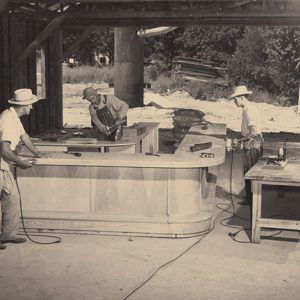 Three white men building an L-shaped counter in garage