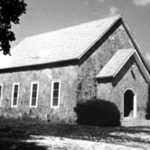 Stone church building with bushes on either side of the entrance