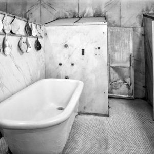 Bath tub with towels and scrubbing mittens hanging on the wall