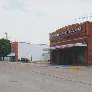 Two-story brick buildings on street with water tower in the background