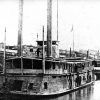 Close-up of naval steamboat at port with buildings and another steamboat in the background