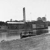 Naval side wheel steamboat on river with sailors in lifeboat landing on shore