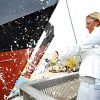 White woman breaking a bottle across the bow of a navy ship