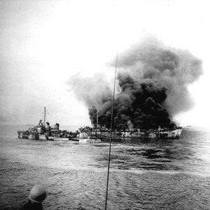 Cloud of smoke billowing from Naval vessel 736 with ship nearby as seen from another vessel at sea