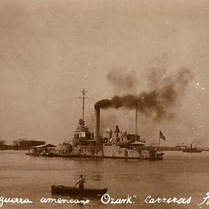 sepia-toned photo of naval steamboat and a smaller boat in the foreground