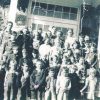 Group of white children and teacher standing on steps of stone building