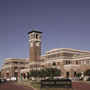 large multistory brick train station with arched entrances and tall bell tower