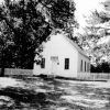 Single-story school building with A-frame roof and fence