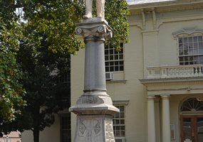 Statue of soldier on stone column with engraved pedestal on court house lawn