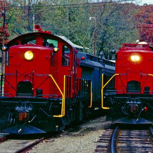 Pair of red trains with cars passing each other on tracks