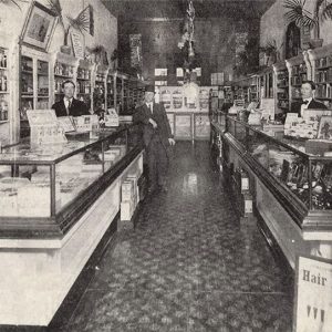 Three white men standing in store with display counters