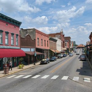 Street with brick storefronts crosswalk and parked cars