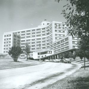 large multistory building with parked cars on paved driveway