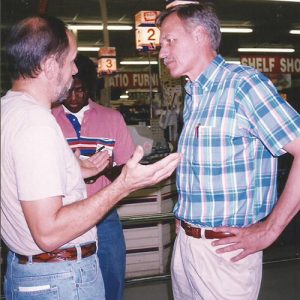 Pair of white men and African American man talking in supermarket