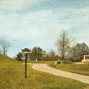 Stone monument with angel statue and walking path with sign