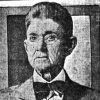 Older white woman dressed as a man with glasses in suit and bow tie