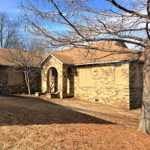 Brick school building with gabled roof and arched covered entrance way