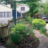 Oval shaped sign "The Writer's Colony at Dairy Hollow" in front garden with house and fence behind it