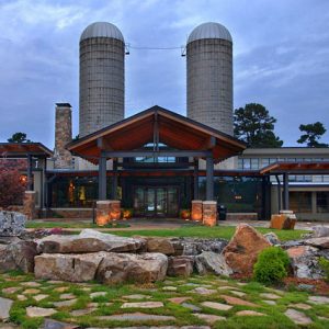 Modern building with covered entrance and walkways and two silos behind it in the background