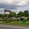 "Wabbaseka Community Park" sign and flag poles on street with single-story buildings and houses in the background