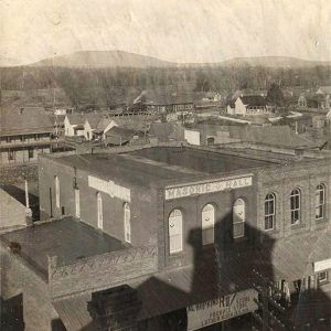 Multistory "Masonic Hall" building with houses and other structures in the background