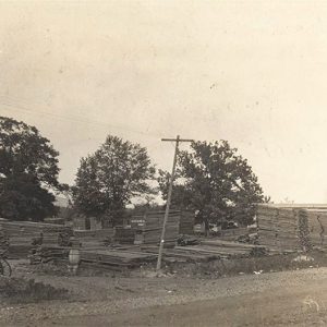 Large stacks of cut lumber with smokestack in the background