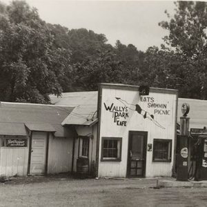 Car parked outside single-story service station building with two gas pumps