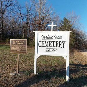 "Walnut Grove Cemetery established 1840" sign with cross and historical marker sign next to dirt road