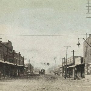 Trolley car on town street with multistory buildings on both sides