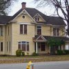 Multistory yellow house with covered porch on street