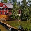 River with green foliage and red barn shaped mill building