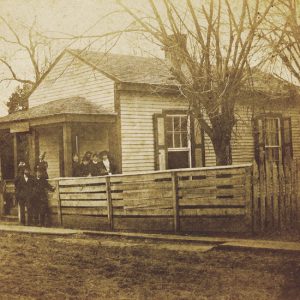 Group of people outside building with wooden fence and trees