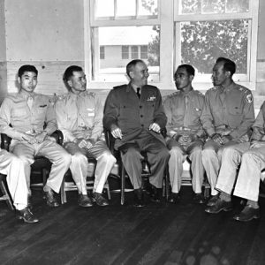 Interior five male Chinese and one white air force officers sit with white admiral near window