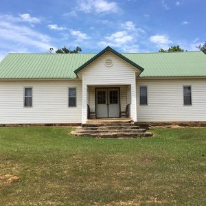 Green and white building with covered entrance and steps