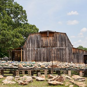 Rows of tables supported by concrete blocks with crystals and rocks with barn in the background