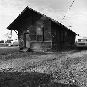 Single-story wooden building with trucks parked outside it