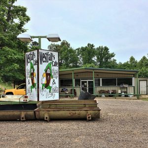 "Westfall's Cafe" sign and single-story building with gravel parking lot