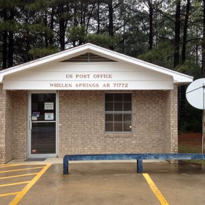 Small brick building with parking lot satellite dish and blue post office box