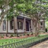 Side view of multistory house with covered porch and balcony inside iron fence with trees in its front yard