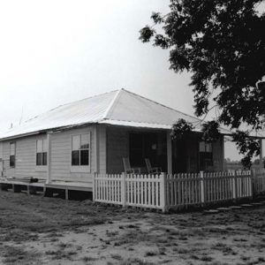 Single-story house with fence and tree in front yard