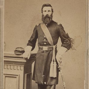 White man with long beard standing in military uniform with sword in hand