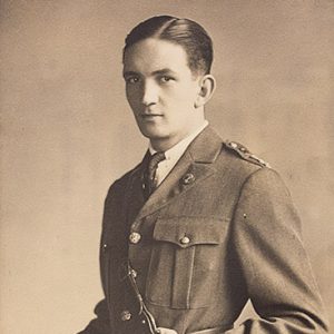 White man standing in military uniform with hands at his waist