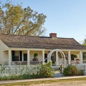 Single-story house with covered porch inside wooden fence