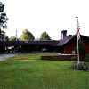 Single-story brick house with flat angled roof driveway and flagpole