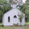 Restored church building with cupola and cemetery behind it