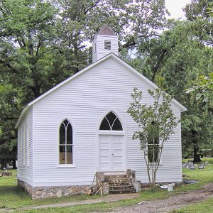 Restored church building with cupola and cemetery behind it