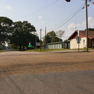 Single-story building with storage building behind it on rural street corner