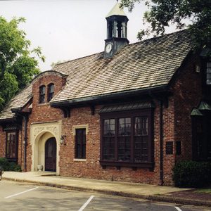 Brick building with tower arched doorway and blue car in parking lot